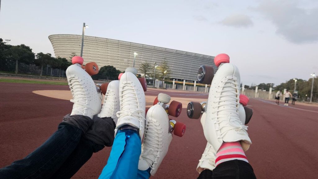 Green Point Open roller skate sessions in Cape Town. 3 sets of white roller skates in front of the DHL Stadium in Green Point.